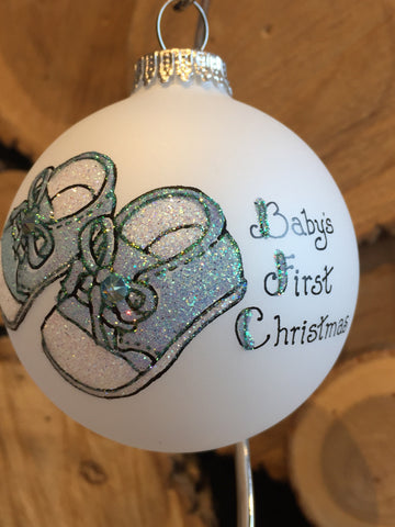 White Frosted Round Ornament depicting blue baby shoes with inscription "Baby's first Christmas"